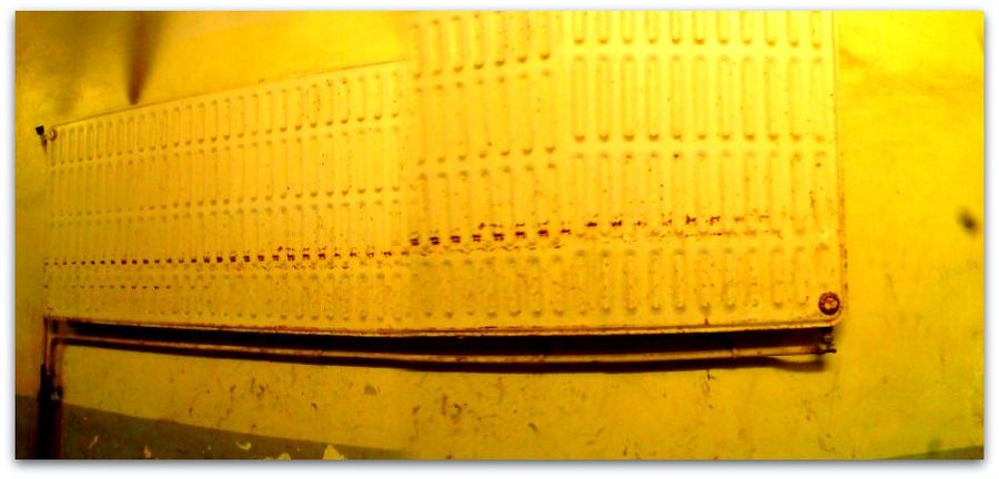 Mur perforé baigné de jaune, panoramique.